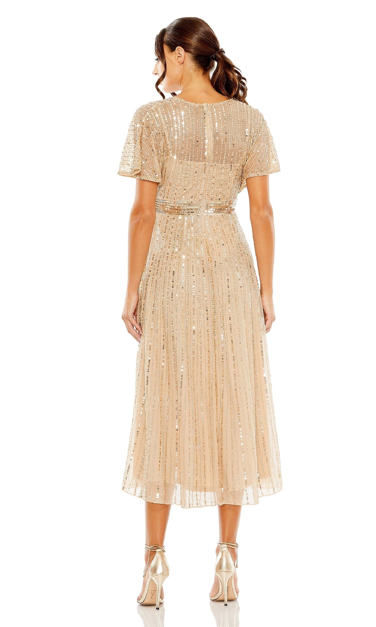 A woman stands with her back to the camera wearing the Mac Duggal 14007 Short Sequin Wedding-Guest Dress in gold and matching high heels—a dazzling semi-formal choice for wedding guests.